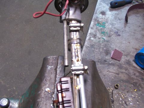 1988 Ford C-350 (Centurion Conversions) - Fuel pump assembly held in a vise, ready for work. Red wire and metal components are visible.