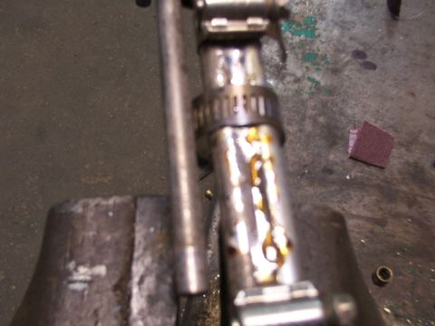 1988 Ford C-350 (Centurion Conversions) - A close-up view of a fuel pump assembly secured in a vise, showing signs of oil residue on the metal tubing.