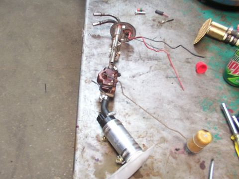 1988 Ford C-350 (Centurion Conversions) - A disassembled fuel pump assembly, including the pump, filter, and associated wiring, lies on a workbench.
