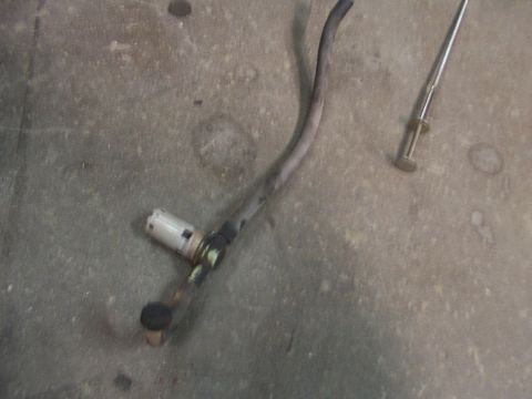 1988 Ford C-350 (Centurion Conversions) - A fuel pump assembly with two hoses and a metal rod lies on a concrete surface.