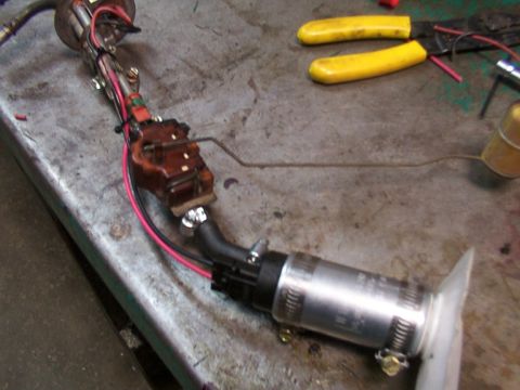 1988 Ford C-350 (Centurion Conversions) - A disassembled fuel pump assembly sits on a workbench next to a pair of yellow-handled pliers.
