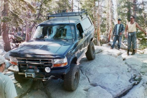 1994 Ford Bronco - A lifted Ford Bronco navigates a rocky trail with two onlookers.