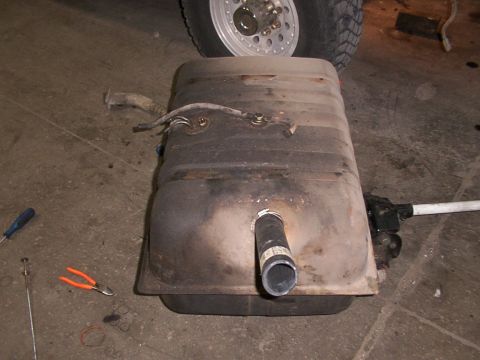 1988 Ford C-350 (Centurion Conversions) - A removed fuel tank is shown on a garage floor, with tools and a vehicle tire visible in the background.