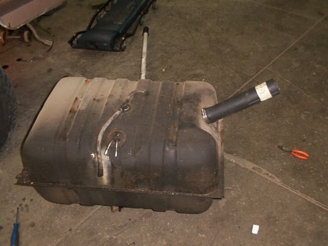 1988 Ford C-350 (Centurion Conversions) - A detached fuel tank sits on a garage floor, showing signs of wear and tear.