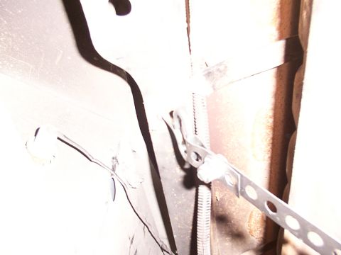1988 Ford C-350 (Centurion Conversions) - Close-up view of metal fuel tank straps on a vehicle's undercarriage.