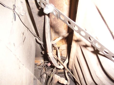1988 Ford C-350 (Centurion Conversions) - Close-up view of the undercarriage, focusing on the fuel tank straps and associated wiring.