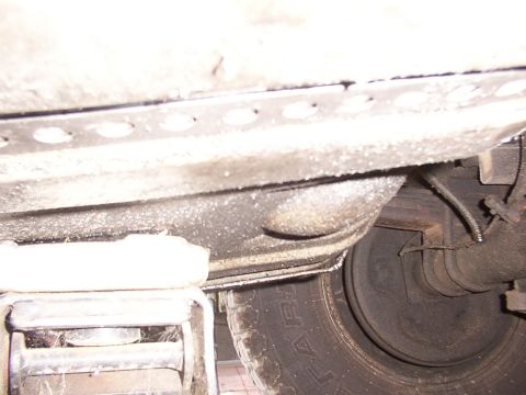 1988 Ford C-350 (Centurion Conversions) - Underside view of a vehicle's fuel tank and tire, with a jack visible for support.