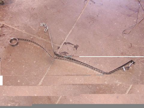 1988 Ford C-350 (Centurion Conversions) - A single fuel tank strap is shown lying on a tiled surface, likely removed from a vehicle.