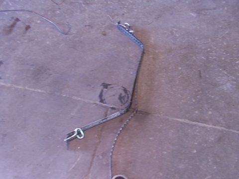 1988 Ford C-350 (Centurion Conversions) - A single fuel tank strap assembly, including a chain and metal brackets, lies on a concrete surface.