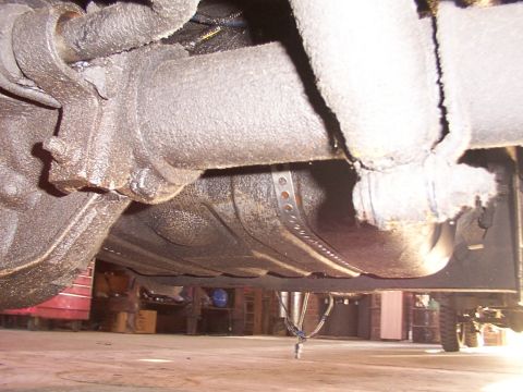 1988 Ford C-350 (Centurion Conversions) - Close-up view of the undercarriage, focusing on the fuel tank straps and a portion of the exhaust system.