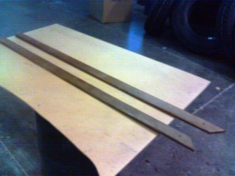 1988 Ford C-350 (Centurion Conversions) - Two wooden trim pieces are laid out on a piece of plywood, possibly for installation.