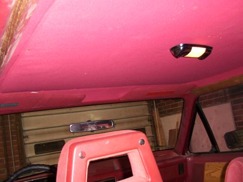 1988 Ford C-350 (Centurion Conversions) - Interior view of a vehicle with a bright pink headliner and red seats, a dome light and rear-view mirror.