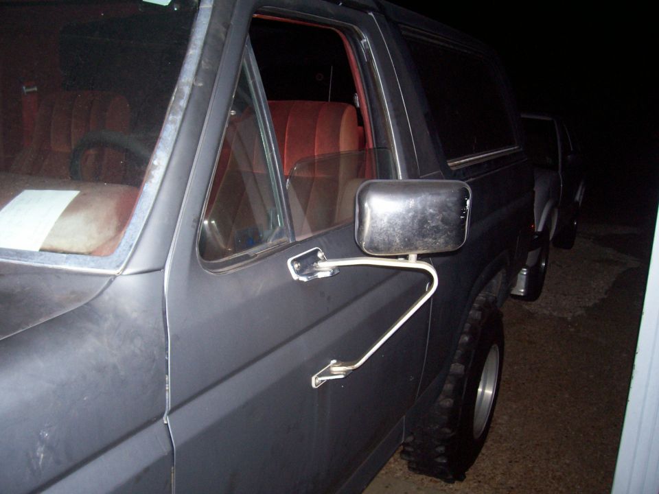 1985 Ford Bronco side door, mirror, and interior detail. Another vehicle is visible in the background