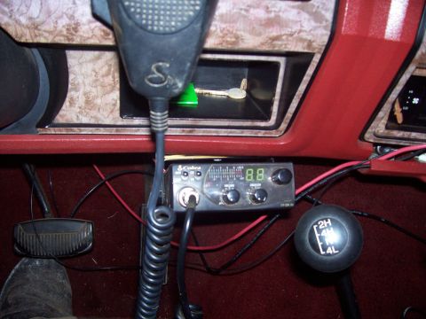 1985 Ford Bronco - The interior of the vehicle features a CB radio and a 4x4 gear shifter, along with a microphone and keys.