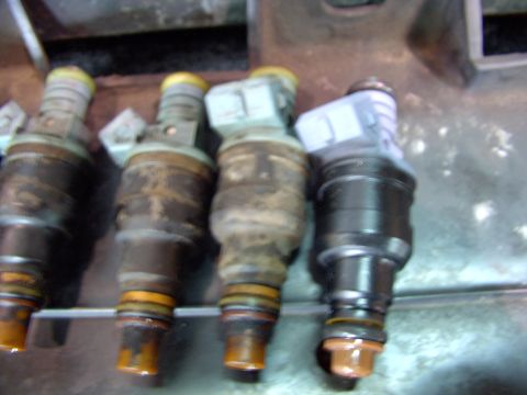 1988 Ford C-350 (Centurion Conversions) - A set of four fuel injectors are shown, with three appearing used and one looking new.