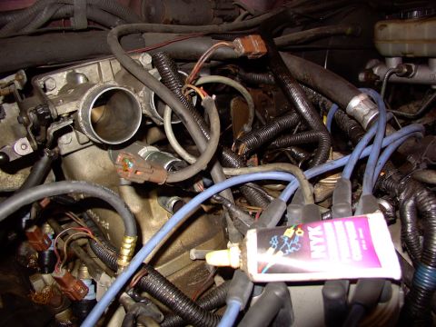 1988 Ford C-350 (Centurion Conversions) - Close-up of engine components including the throttle body, fuel injectors, and spark plug wires, with a tube of grease visible.