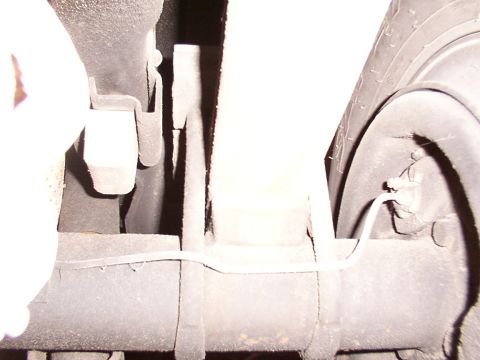 1988 Ford C-350 (Centurion Conversions) - Close-up view of the rear axle and suspension components, including a brake line and part of the tire.