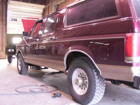 1988 Ford C-350 (Centurion Conversions) - A maroon Ford Bronco with tan lower body panels is parked inside a garage with its hood open.
