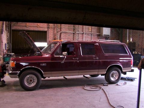 1988 Ford C-350 (Centurion Conversions) - Maroon Ford Bronco SUV with hood open, parked inside a garage.