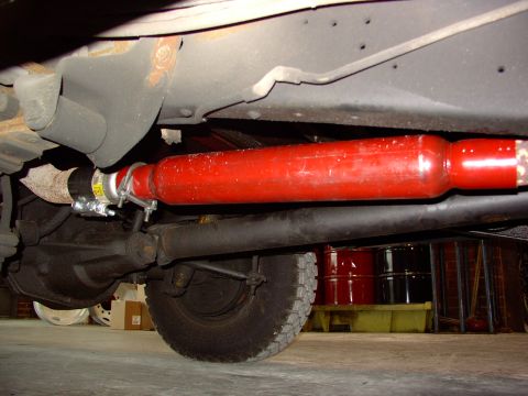 1988 Ford C-350 (Centurion Conversions) - Close-up view of a vehicle's exhaust system and rear axle, with visible text on a clamp.