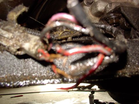 1988 Ford C-350 (Centurion Conversions) - Close-up of frayed wiring harness connected to a greasy mechanical component, likely part of a vehicle's drivetrain.