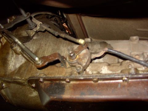 1988 Ford C-350 (Centurion Conversions) - Close-up view of the transmission shift linkage mechanism, showing rusty metal components and cables.