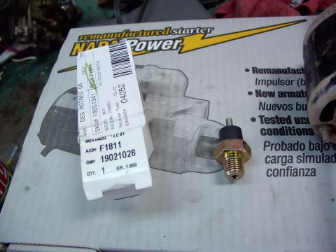 1988 Ford C-350 (Centurion Conversions) - A close-up of an oil pressure sending unit and its packaging, with a NAPA Power starter box in the background.