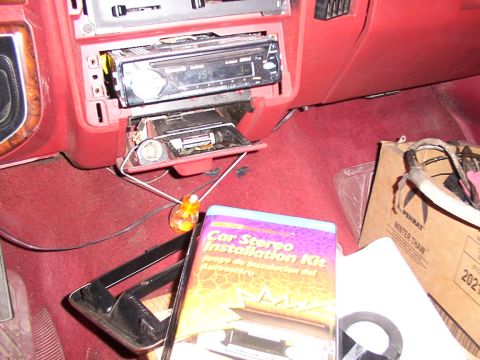 1988 Ford C-350 (Centurion Conversions) - A car interior shows a stereo installation kit box and wiring on the red carpeted floor.