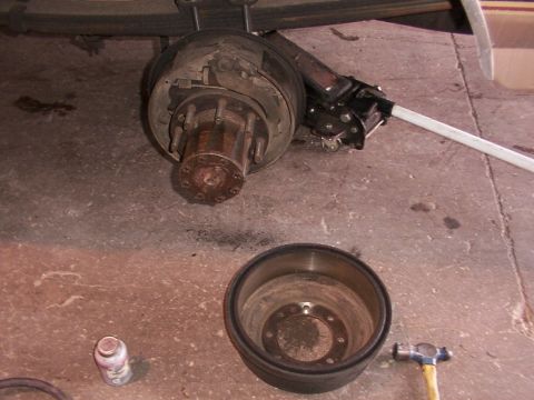1988 Ford C-350 (Centurion Conversions) - A disassembled rear brake drum and hub assembly is shown with tools on a concrete surface.