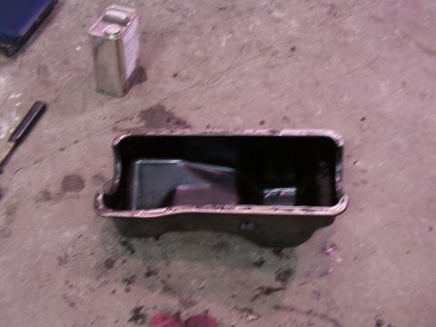 1988 Ford C-350 (Centurion Conversions) - An oil pan sits on a concrete floor next to a metal can and a tool.