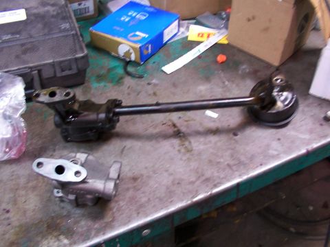1988 Ford C-350 (Centurion Conversions) - Two oil pump components, one with a drive shaft, are laid out on a metal workbench.