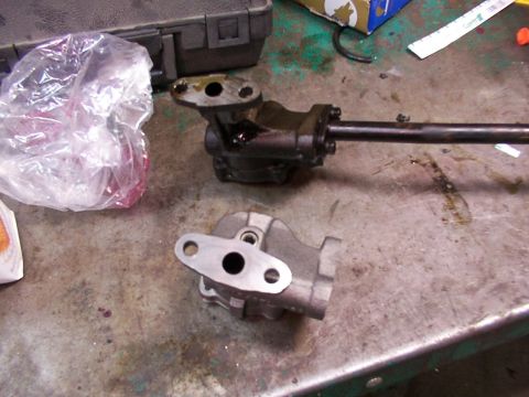 1988 Ford C-350 (Centurion Conversions) - Two oil pump assemblies and a drive shaft are laid out on a cluttered workbench.