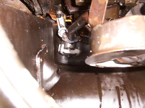 1988 Ford C-350 (Centurion Conversions) - Close-up view of an engine's oil pan and oil pump assembly, showing signs of oil leakage.