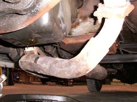 1988 Ford C-350 (Centurion Conversions) - Close-up view of the undercarriage of a vehicle, focusing on the exhaust system and oil pan.