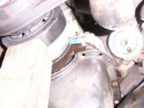 1988 Ford C-350 (Centurion Conversions) - Close-up view of an engine's oil pan and crankshaft seal area, with visible sealant and a supporting block.