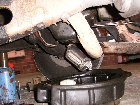 1988 Ford C-350 (Centurion Conversions) - Oil filter removal and oil drain pan positioned beneath the vehicle's undercarriage.