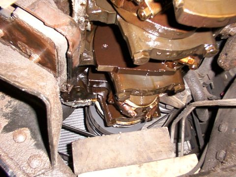 1988 Ford C-350 (Centurion Conversions) - Close-up view of the engine's crankshaft and oil pan area, showing signs of oil leakage.