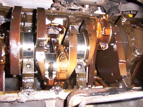 1988 Ford C-350 (Centurion Conversions) - Close-up view of the engine's crankshaft and connecting rods, showing signs of oil leakage.