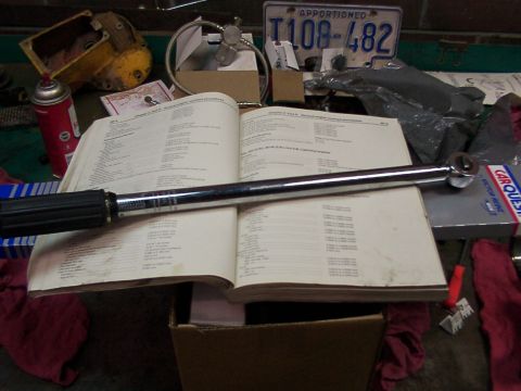 1988 Ford C-350 (Centurion Conversions) - Service manual open with a torque wrench. Other auto parts and a license plate are visible.