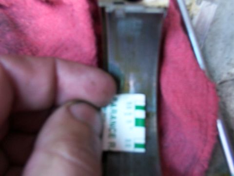 1988 Ford C-350 (Centurion Conversions) - A hand holds a measurement tool against an engine bearing, with a red cloth visible.