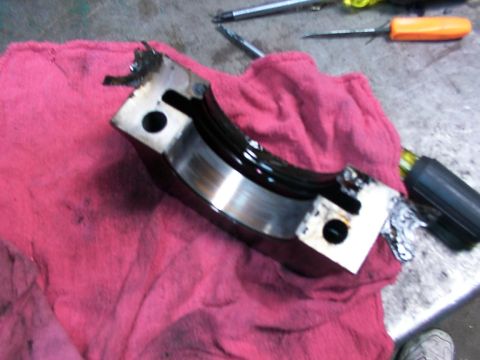 1988 Ford C-350 (Centurion Conversions) - Damaged engine bearing cap with debris, resting on a red shop towel next to tools.