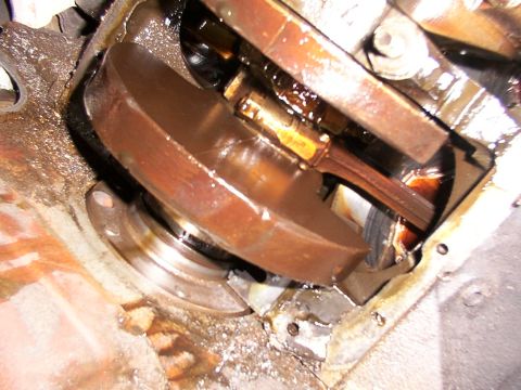 1988 Ford C-350 (Centurion Conversions) - Close-up view of internal engine components, likely a crankshaft and connecting rod, showing oil accumulation.