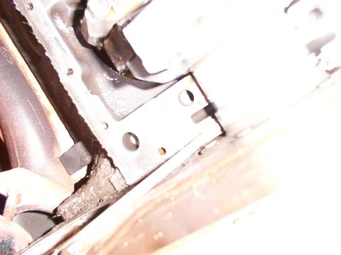 1988 Ford C-350 (Centurion Conversions) - Close-up view of a metal bracket and bolts on a vehicle's undercarriage, possibly related to the rear main seal area.