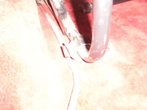 1988 Ford C-350 (Centurion Conversions) - Close-up of a metal seat mounting bracket against a red carpeted surface.