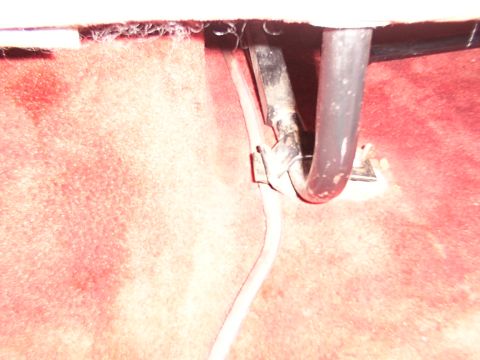 1988 Ford C-350 (Centurion Conversions) - Close-up view of the metal bracket and tubing for a rear seat mount, set against a red carpeted floor.