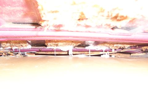 1988 Ford C-350 (Centurion Conversions) - The underside of a vehicle shows exposed insulation and wiring, with sealant applied.