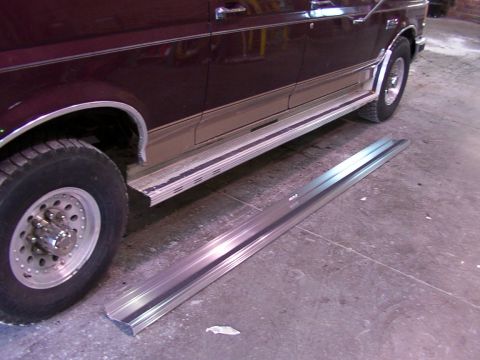 1988 Ford C-350 (Centurion Conversions) - Running boards removed from a vehicle, placed on the floor beside the vehicle.
