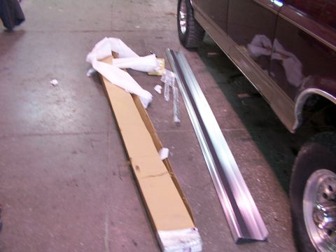 1988 Ford C-350 (Centurion Conversions) - Unboxed running boards are laid out on the floor next to a maroon vehicle.