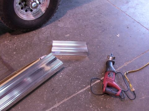 1988 Ford C-350 (Centurion Conversions) - Aluminum running boards are cut and a reciprocating saw lies on the concrete floor.