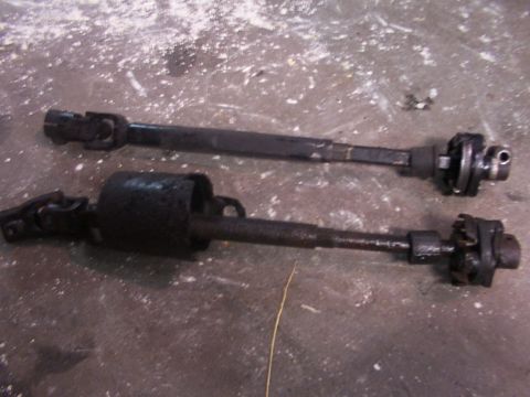 1988 Ford C-350 (Centurion Conversions) - Two steering shafts, one with a larger diameter housing, lie on a textured concrete floor.